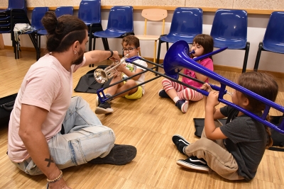 Tres infants aprenen a tocar la trompeta i el trombó.