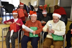 Les persones grans del menjador social obren l'obsequi lliurat per Volumont.