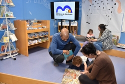 Famílies llegint a la tarima de la sala infantil.