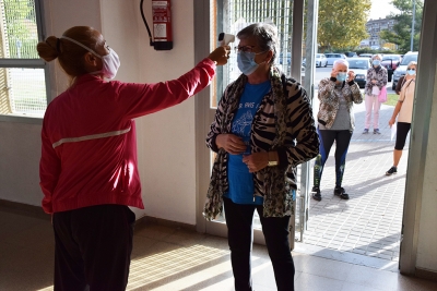 Abans d'entrar a l'espai la monitora del taller pren la temperatura als usuaris i usuàries