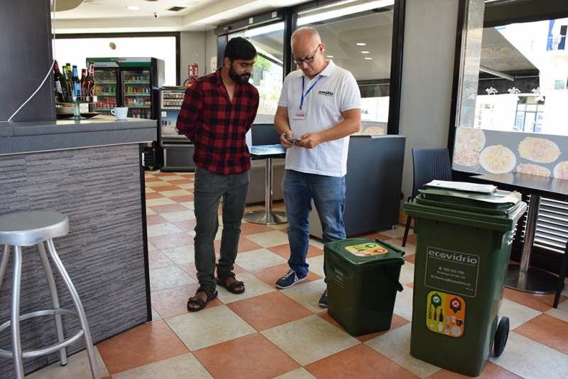 Un informador ambiental explica i verifica la correcta separació dels envasos de vidre a un establiment de Montornès.