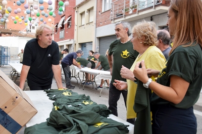 Veïns i veïnes del carrer de l'Estrella repartint les samarretes i els mocadors.